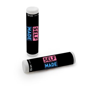 white lip balm with an imprint of a black background and in the middle is text in pink and blue saying self made