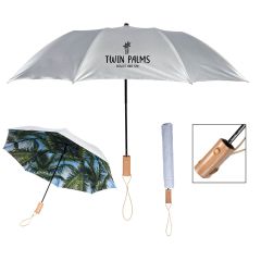 a silver umbrella with a palm tree underside, wrist strap, wood handles, and an imprint saying Twin Palms Resort And Spa