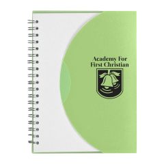 frosted white and green spiral notebook with an imprint of two bells and text above saying academy for first christian